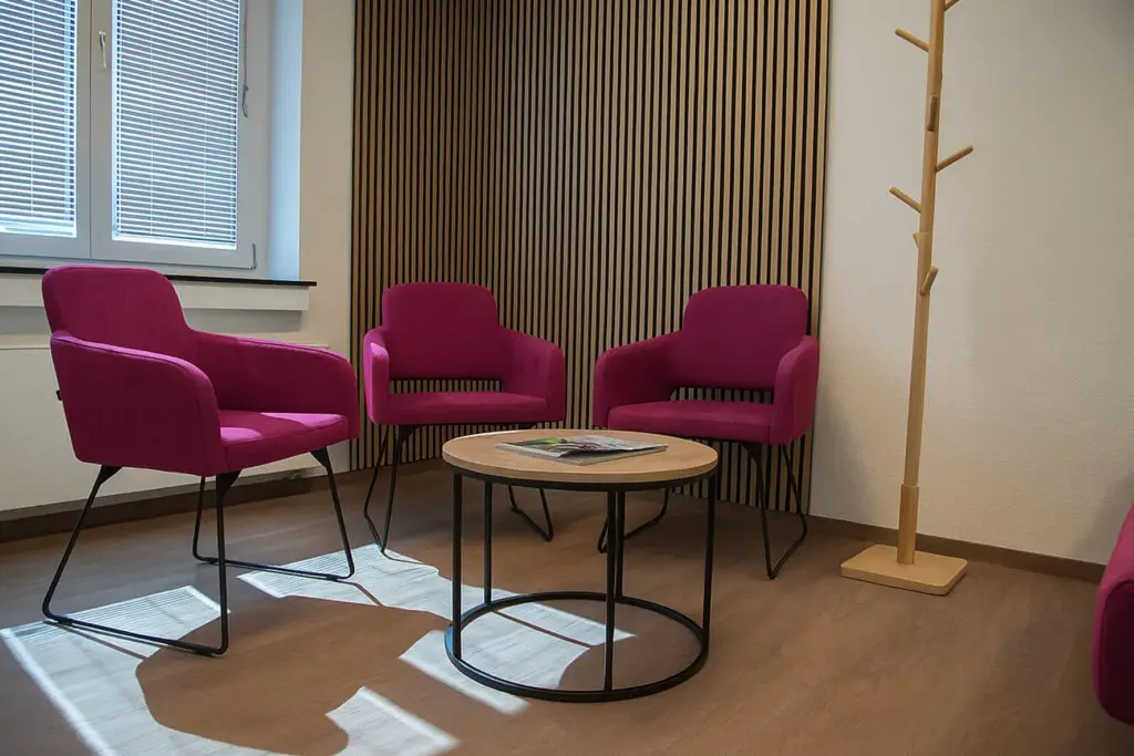 Foto von einem Wartebereich Arztpraxis, Sessel Marvin mit Drahtuntergestell, Polster in pink, Lounge Tisch rund, Schniedersitzt