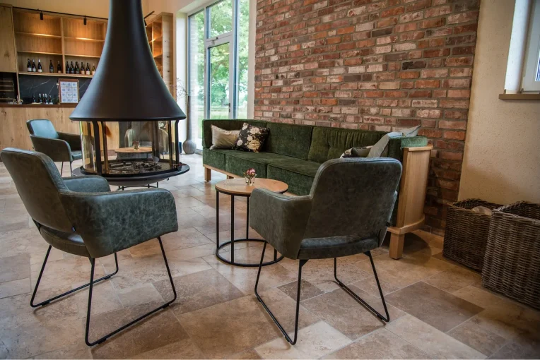 Foto Einrichtung Trüffelscheune Event-Location, Sitzgruppe am Kamin, Diner Sofa Michel, Sessel Marvin Bezug Leder grün, Lounge-Tische