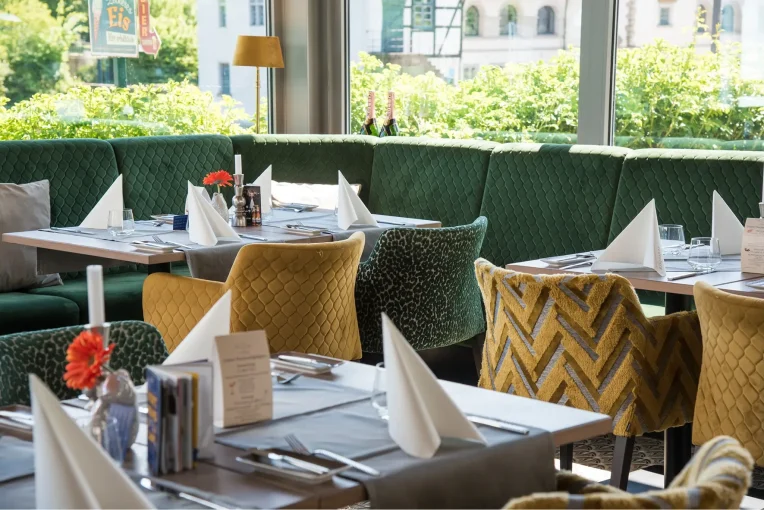 Möbel im Wintergarten Restaurant Rodenberg 1770, Polsterbank Emmi grün, Polstersessel Luisa in gelb und grün, Säulentische Christian